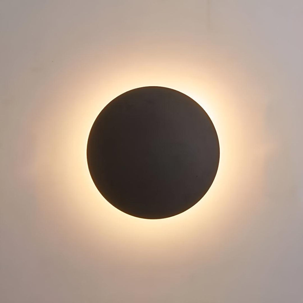 Round LED wall light beside a bed